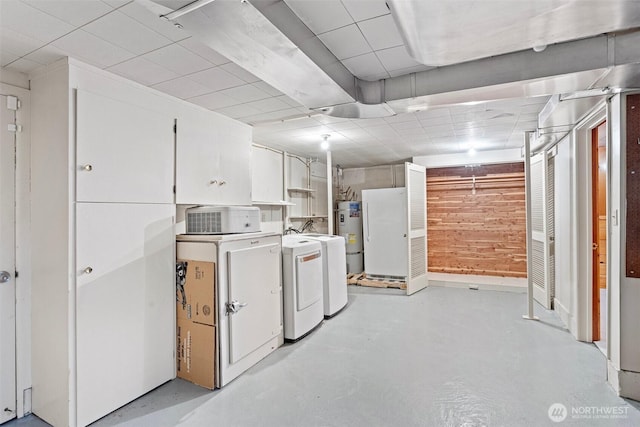 basement featuring fridge, independent washer and dryer, wooden walls, and secured water heater