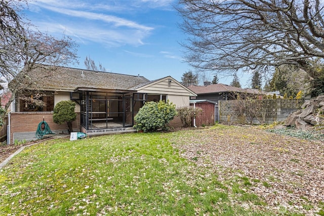 rear view of property featuring a shed and a lawn