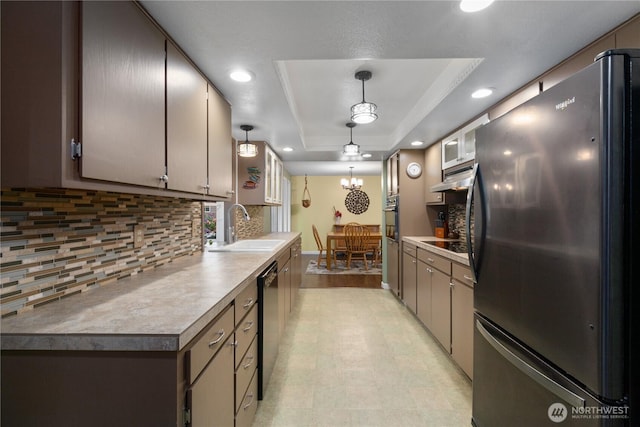 kitchen with oven, freestanding refrigerator, a tray ceiling, pendant lighting, and a sink