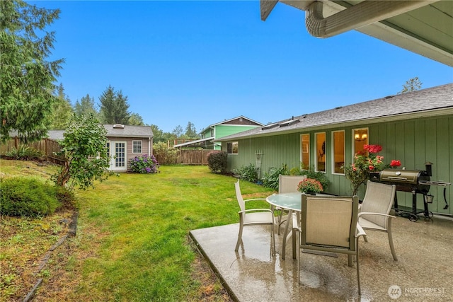 view of yard featuring fence, outdoor dining area, a patio, and an outdoor structure