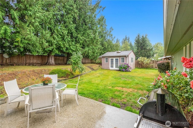 view of yard featuring outdoor dining space, a fenced backyard, an outdoor structure, and a patio