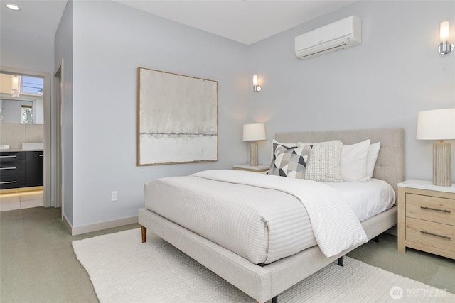 bedroom featuring an AC wall unit, carpet flooring, connected bathroom, and baseboards