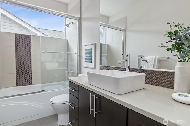 bathroom featuring enclosed tub / shower combo, vanity, and toilet