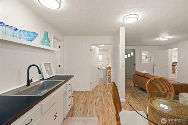 1508 Hoquiam Ln S, Westport, WA 98595 - kitchen with white cabinetry, sink, light hardwood / wood-style flooring, and a textured ceiling