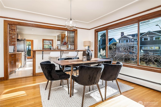 dining space with light wood-style flooring, a baseboard heating unit, and baseboards