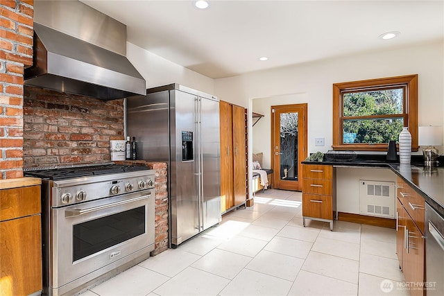 kitchen featuring brown cabinetry, high quality appliances, ventilation hood, and recessed lighting