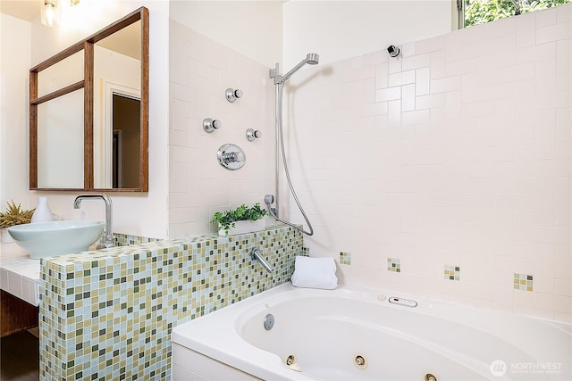 full bathroom with tile walls, a tile shower, a jetted tub, and a sink