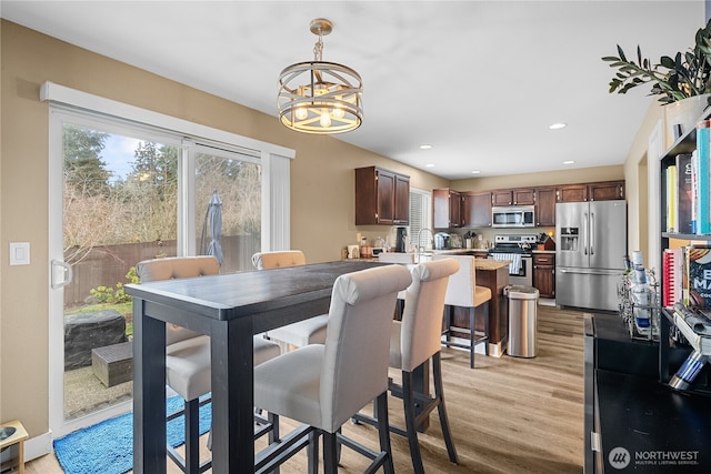 dining space with an inviting chandelier and light hardwood / wood-style flooring