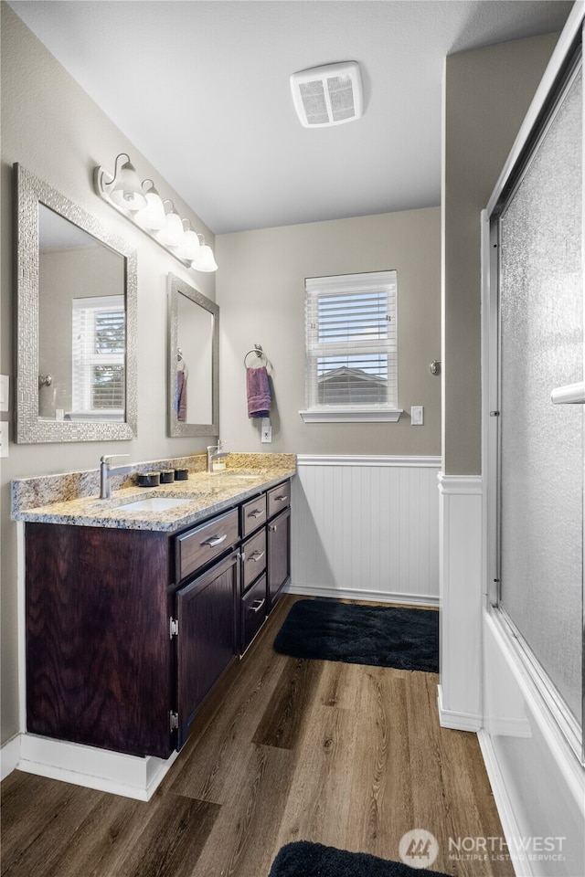 bathroom with a healthy amount of sunlight, wood-type flooring, enclosed tub / shower combo, and vanity