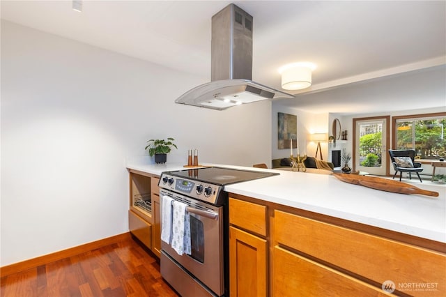 kitchen featuring stainless steel electric range oven, island exhaust hood, dark wood finished floors, and light countertops