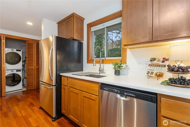 kitchen featuring stacked washer and dryer, dark wood-style flooring, a sink, light countertops, and appliances with stainless steel finishes