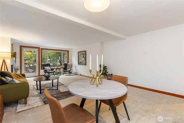 dining room with a baseboard heating unit, light carpet, and baseboards