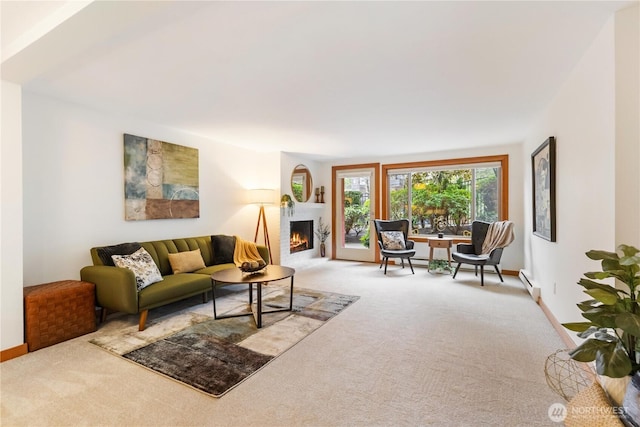 living room with a lit fireplace, baseboard heating, carpet, and baseboards