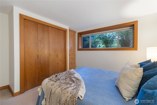 bedroom featuring a closet, light carpet, and baseboards