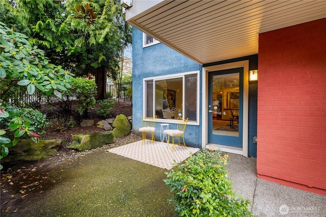 property entrance featuring a patio, fence, and stucco siding