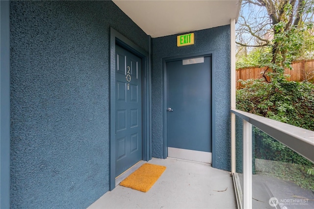 property entrance with fence and stucco siding