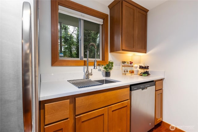 kitchen featuring dishwasher, light countertops, brown cabinetry, and a sink