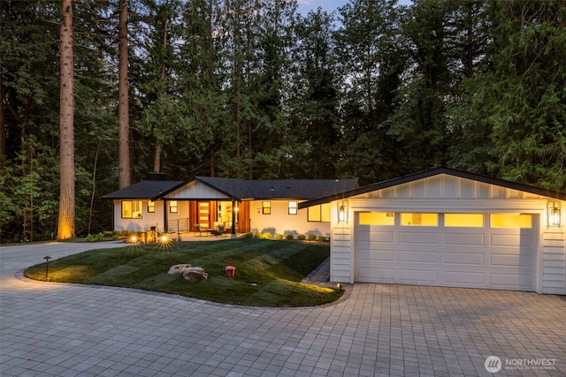 ranch-style home with a garage and a front lawn