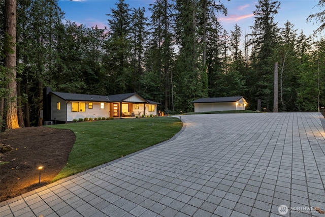 single story home with a yard, a garage, and an outbuilding