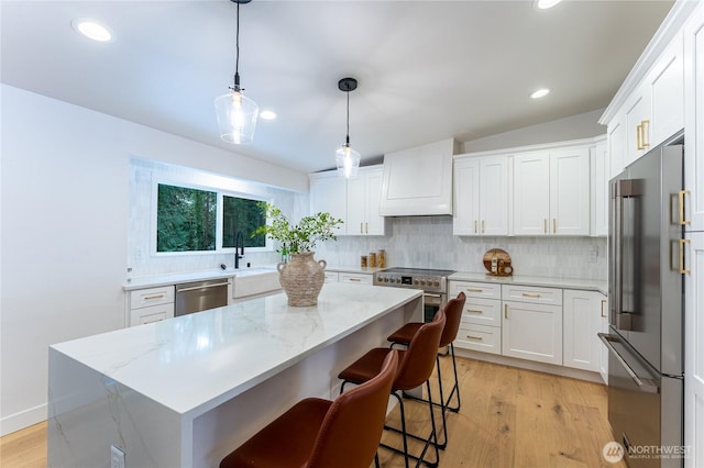 kitchen featuring appliances with stainless steel finishes, custom exhaust hood, white cabinets, and a center island