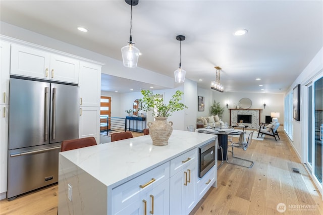 kitchen with a kitchen island, stainless steel appliances, white cabinetry, and pendant lighting