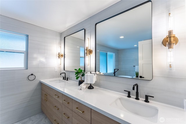 bathroom with tile walls, vanity, and a healthy amount of sunlight