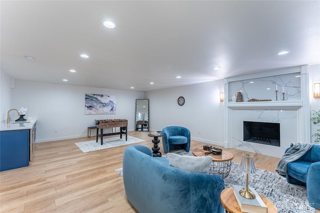 living room with light hardwood / wood-style flooring, a premium fireplace, and sink