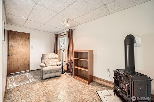 sitting room with a wood stove and a drop ceiling