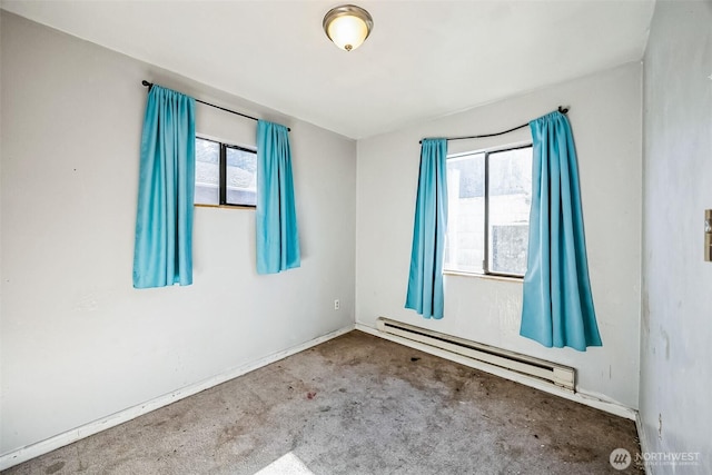 carpeted spare room with a baseboard heating unit