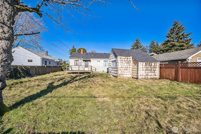 back of property featuring a yard, a deck, and a storage unit