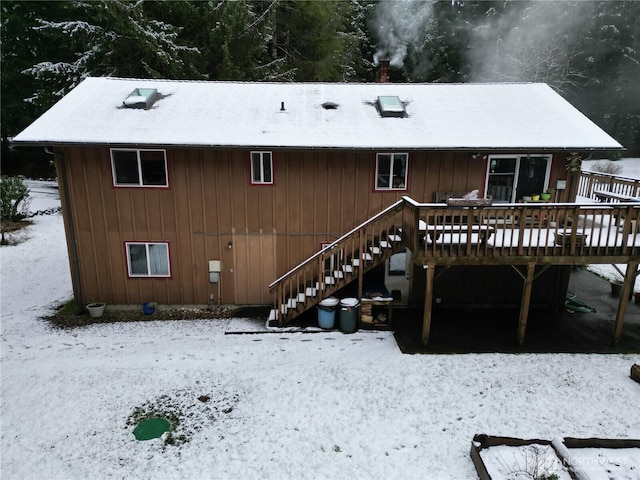 snow covered rear of property with a deck