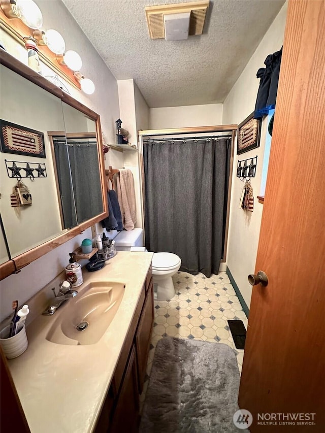 bathroom featuring vanity, curtained shower, toilet, and a textured ceiling