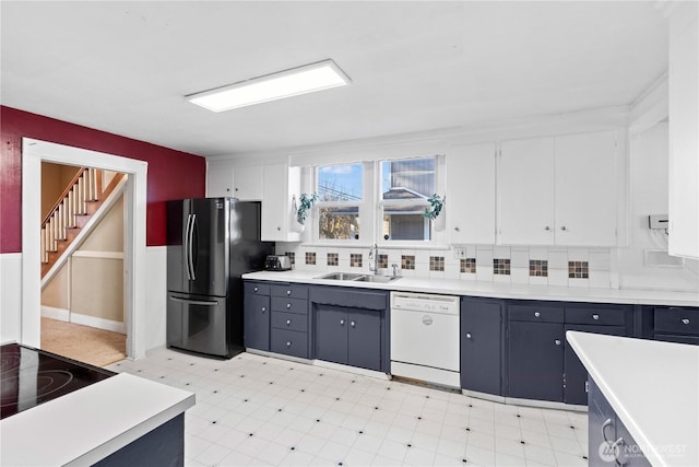 kitchen featuring blue cabinets, sink, white cabinetry, stainless steel refrigerator, and white dishwasher