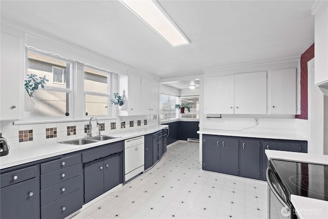 kitchen with range with electric cooktop, tasteful backsplash, white cabinetry, sink, and white dishwasher