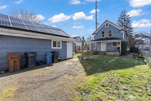 back of property with a lawn and solar panels