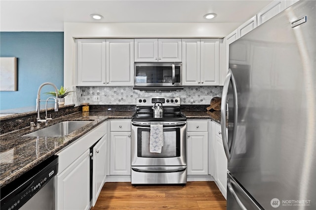 kitchen with dark stone countertops, sink, white cabinets, and appliances with stainless steel finishes