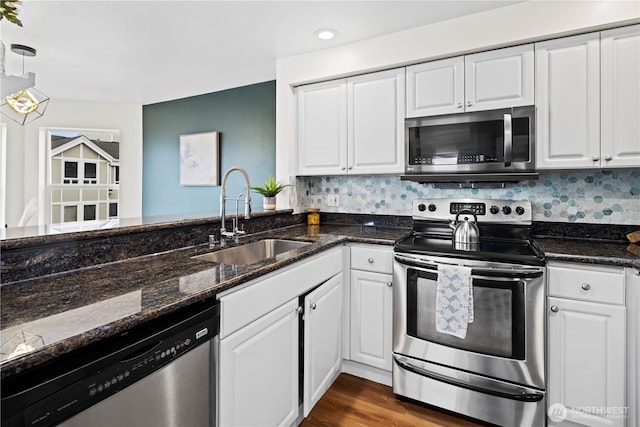 kitchen featuring pendant lighting, sink, white cabinets, dark stone counters, and stainless steel appliances