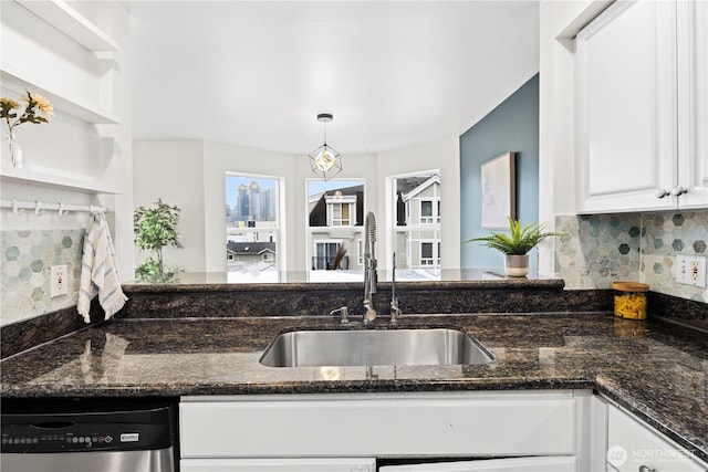 kitchen featuring decorative light fixtures, sink, white cabinets, dark stone counters, and stainless steel dishwasher