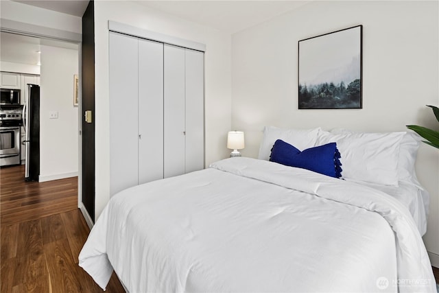 bedroom with a closet, dark hardwood / wood-style floors, and stainless steel refrigerator