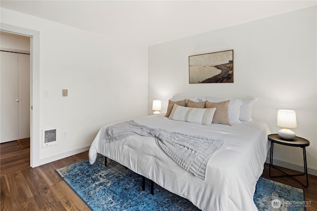 bedroom featuring heating unit and dark hardwood / wood-style flooring