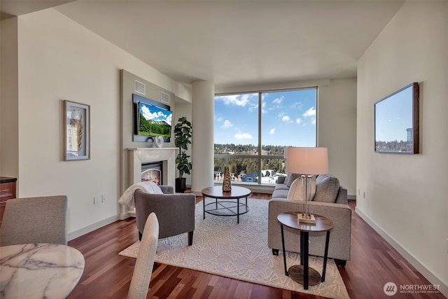 living room featuring a wall of windows, a high end fireplace, and dark hardwood / wood-style floors