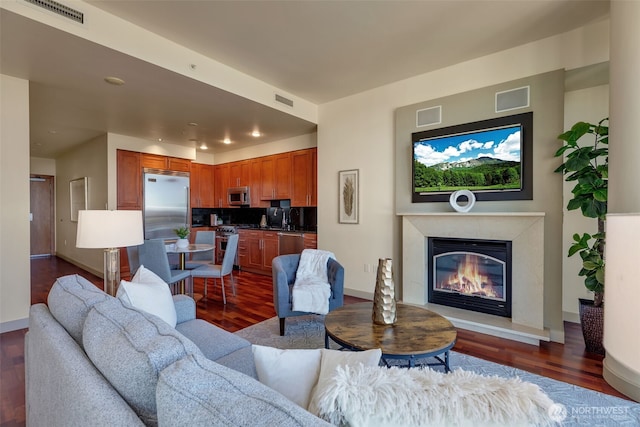 living room featuring sink, dark wood-type flooring, and a premium fireplace