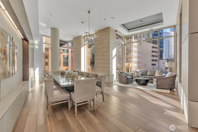 dining room with expansive windows, a raised ceiling, and light wood-type flooring