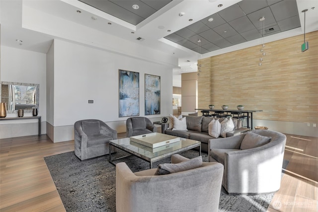 living room featuring hardwood / wood-style flooring, a tray ceiling, a towering ceiling, and wood walls