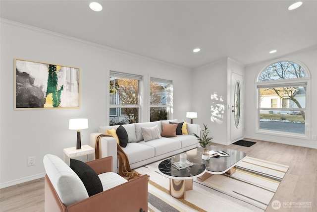 living room with ornamental molding, a healthy amount of sunlight, and light wood-type flooring