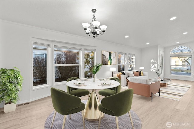 dining area with a notable chandelier, light hardwood / wood-style flooring, and ornamental molding