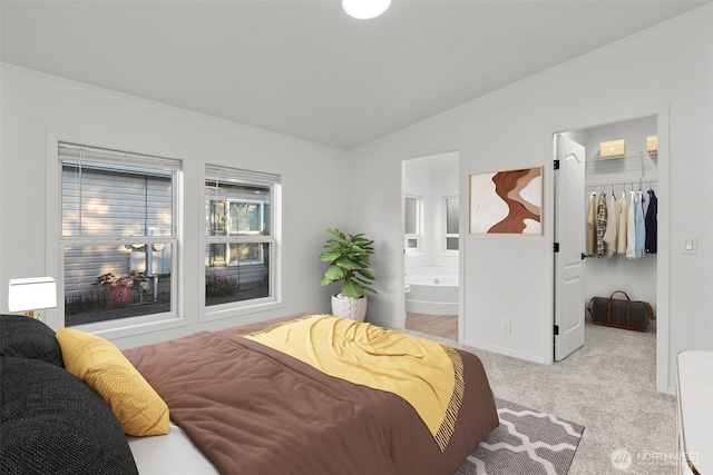 bedroom with ensuite bath, a spacious closet, vaulted ceiling, light carpet, and a closet