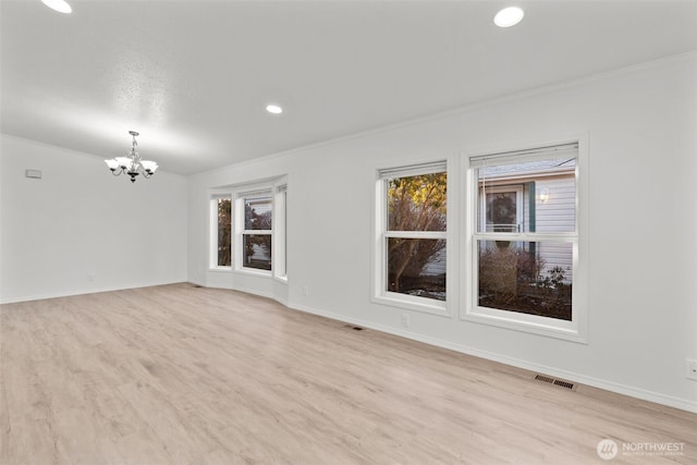 spare room featuring ornamental molding, a chandelier, and light wood-type flooring