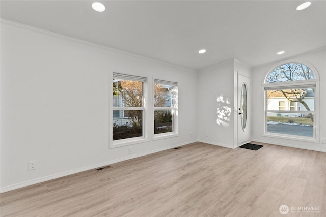 entryway with ornamental molding and light wood-type flooring