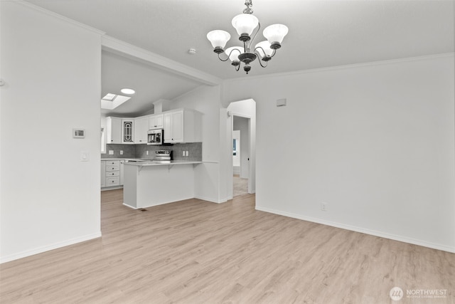 kitchen featuring lofted ceiling with skylight, an inviting chandelier, white cabinets, decorative backsplash, and light wood-type flooring